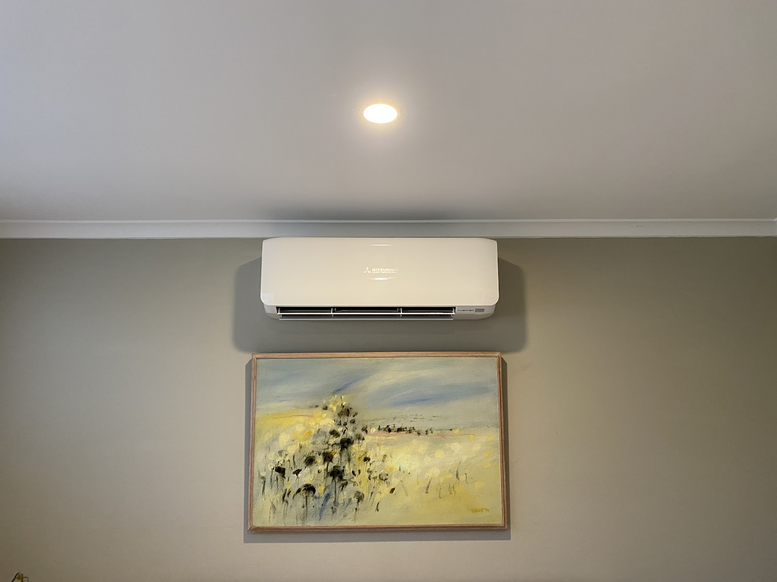A split system wall unit above a framed painting