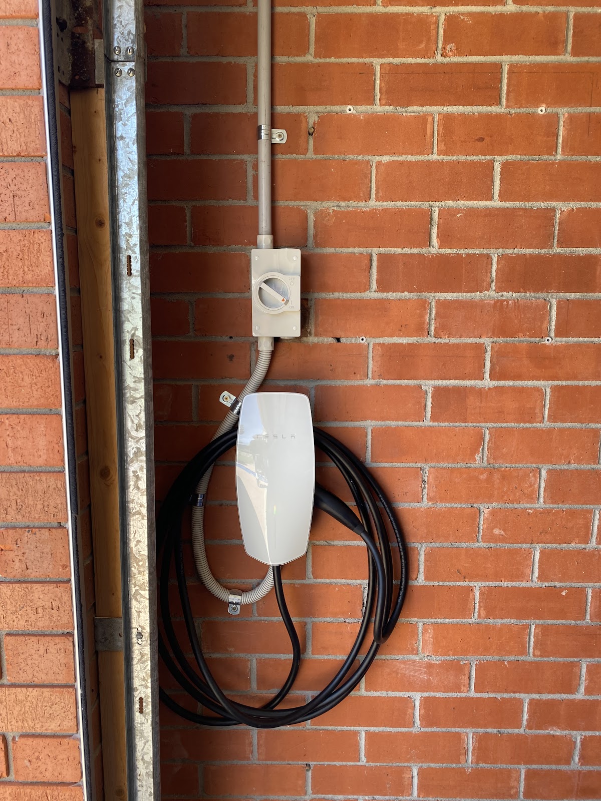 An EV charger installed on a brick garage wall