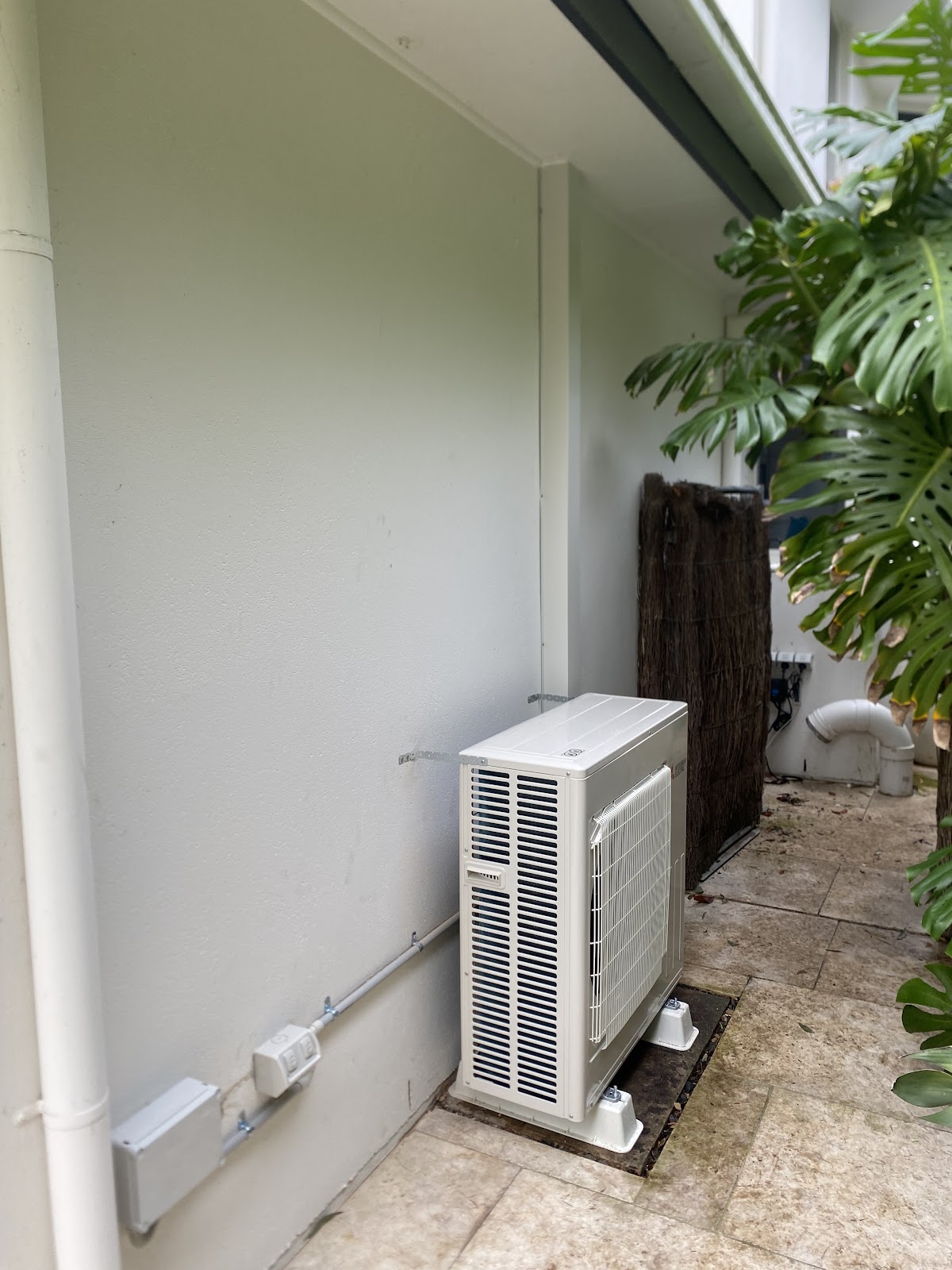 Outdoor air conditioning unit on pavers in a side courtyard